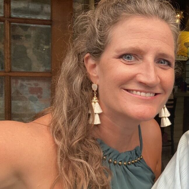 Smiling woman wearing tassel earrings and teal top